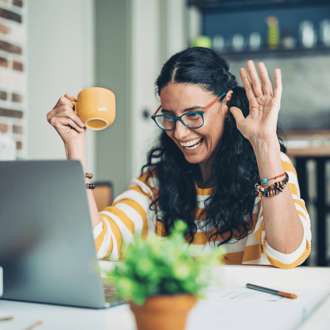 a woman with a mug waving to her computer