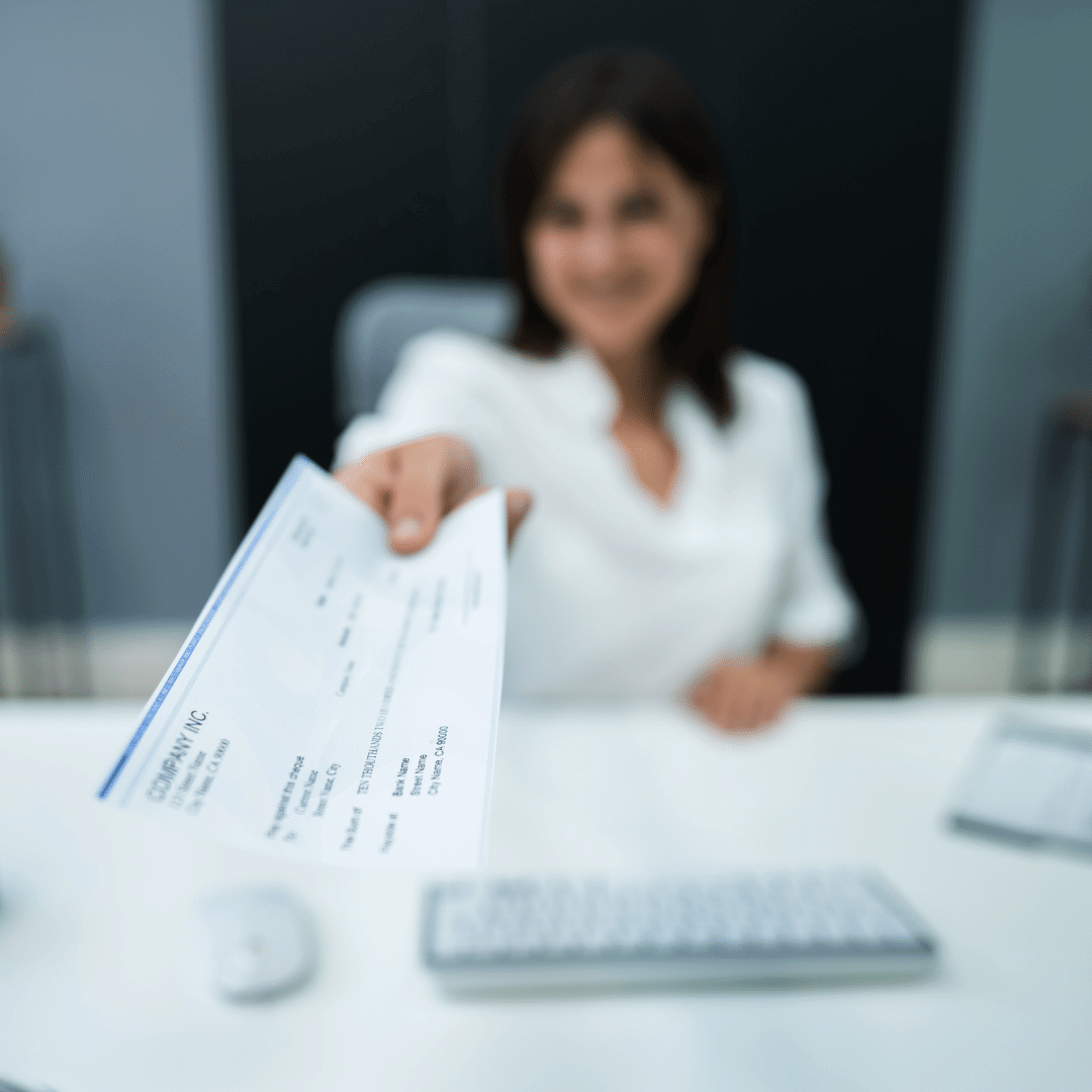 a woman handing a paycheck to the camera