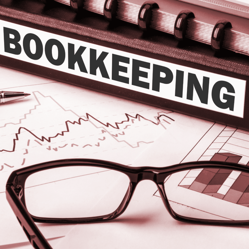 A binder with the word "bookkeeping" on the spine, sitting on top of a paper with a graph and glasses are sitting at the front of the image